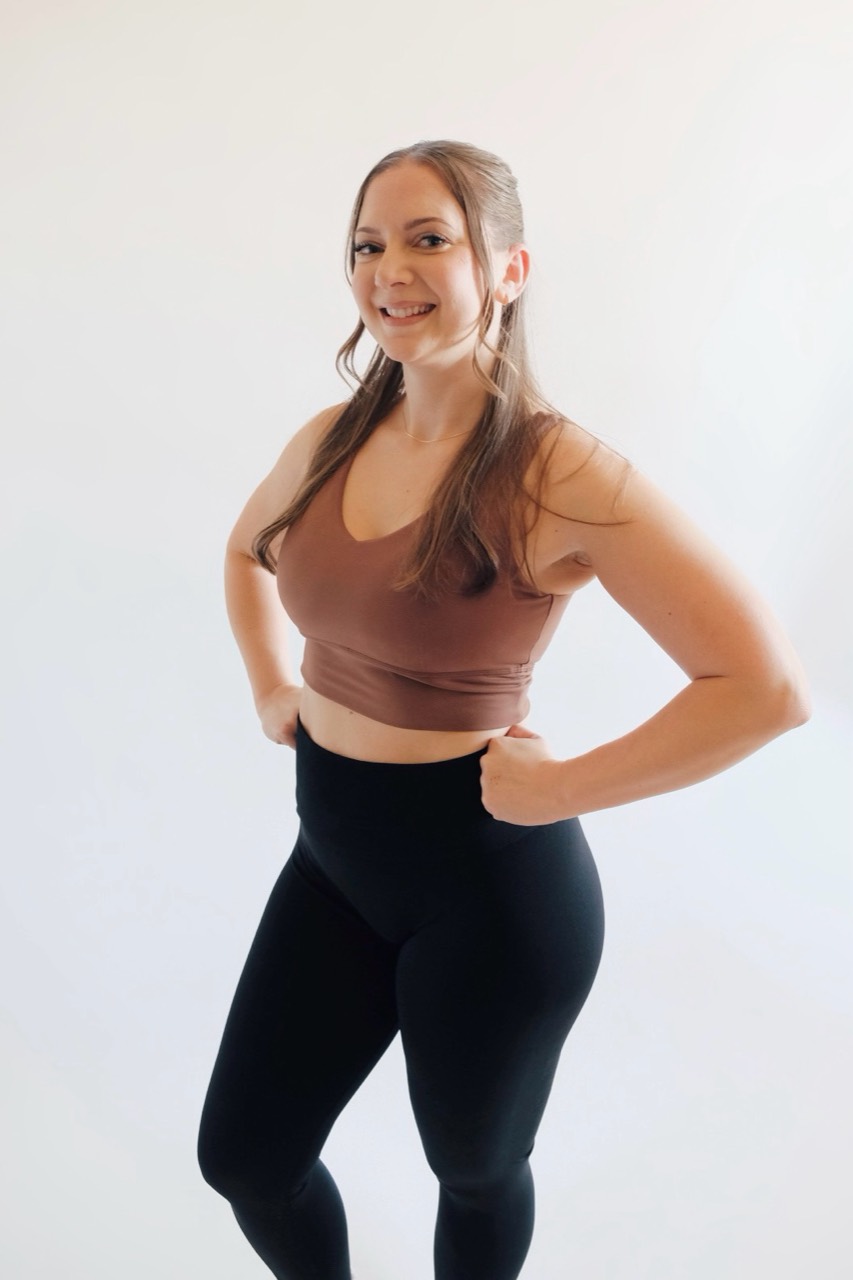 Coach Mel smiling in a brown workout top and black leggings